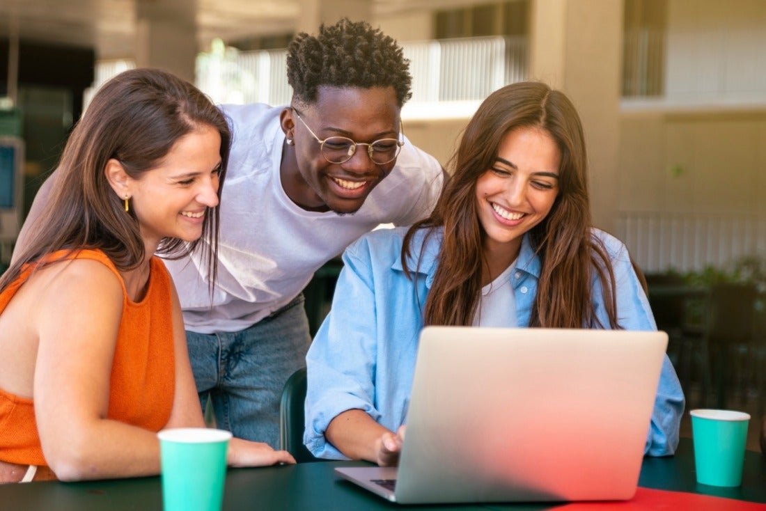 Group of happy coworkers, smiling at a computer
