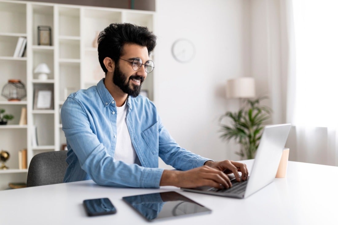 Young professional working on laptop and smiling