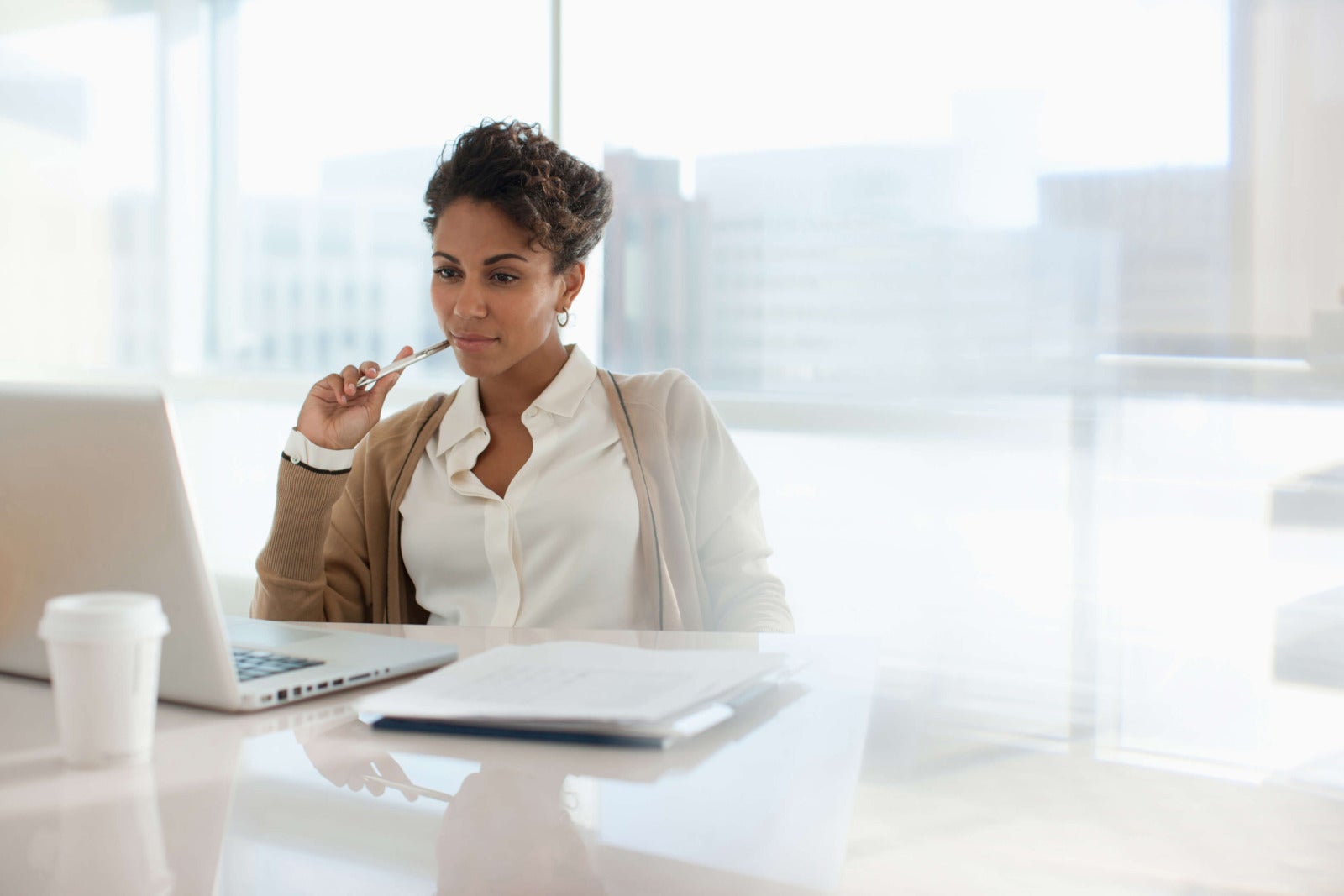 well dressed business professional sits at desk looking at computer